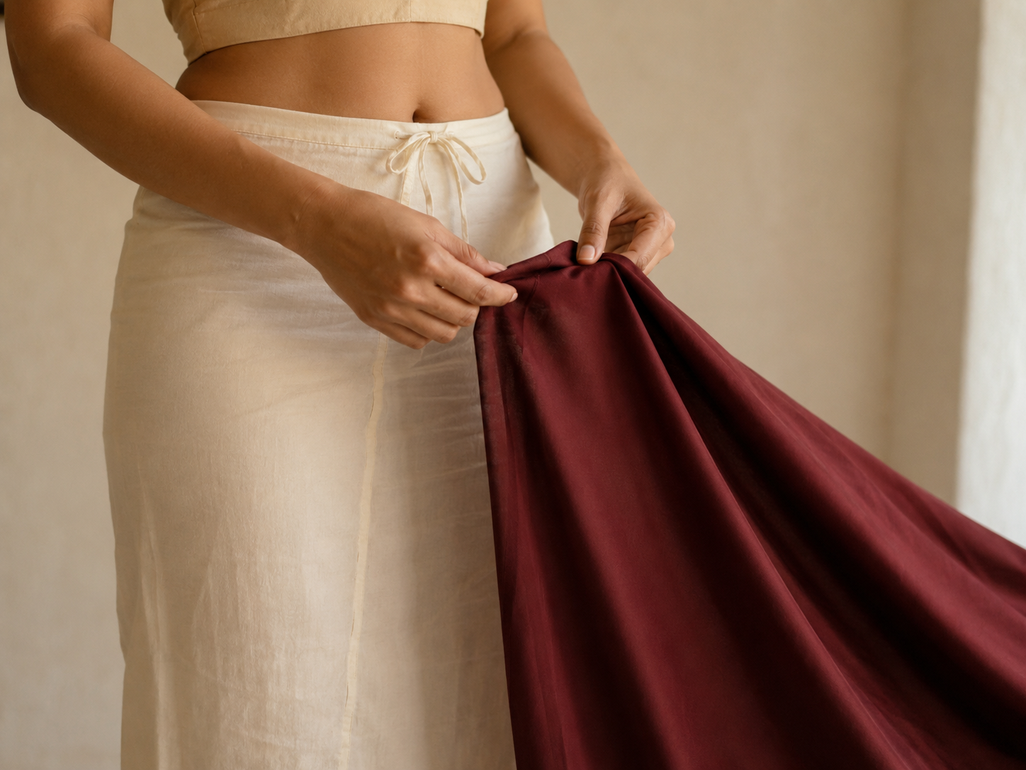 A cream petticoat tied at natural waist with the plain end of a saree held ready to drape