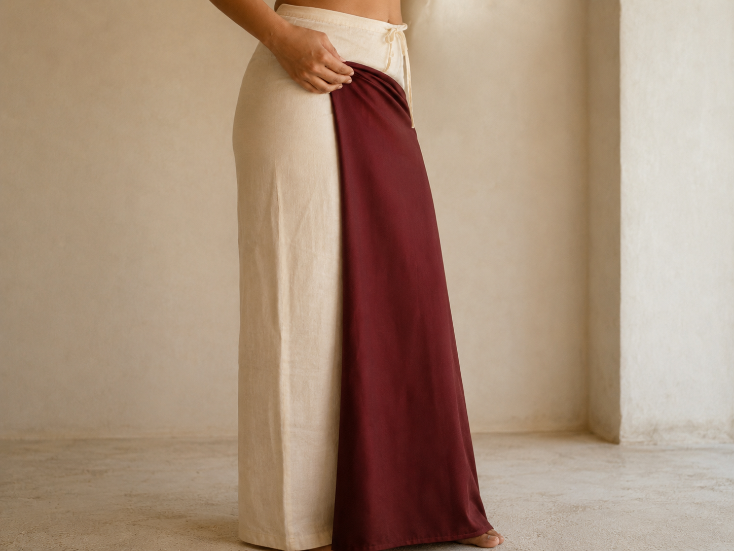 The plain end of a saree tucked into the petticoat at the right hip with the fabric falling to the floor