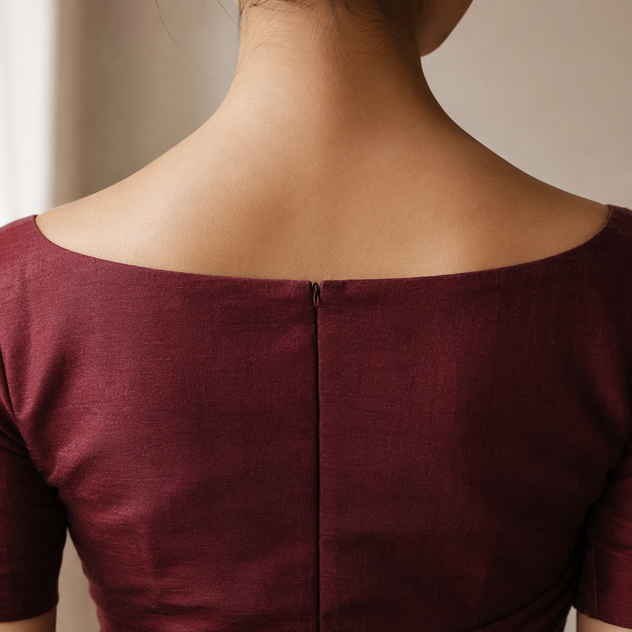 Back view of a fitted saree blouse showing the shoulder seam sitting precisely on the shoulder bone