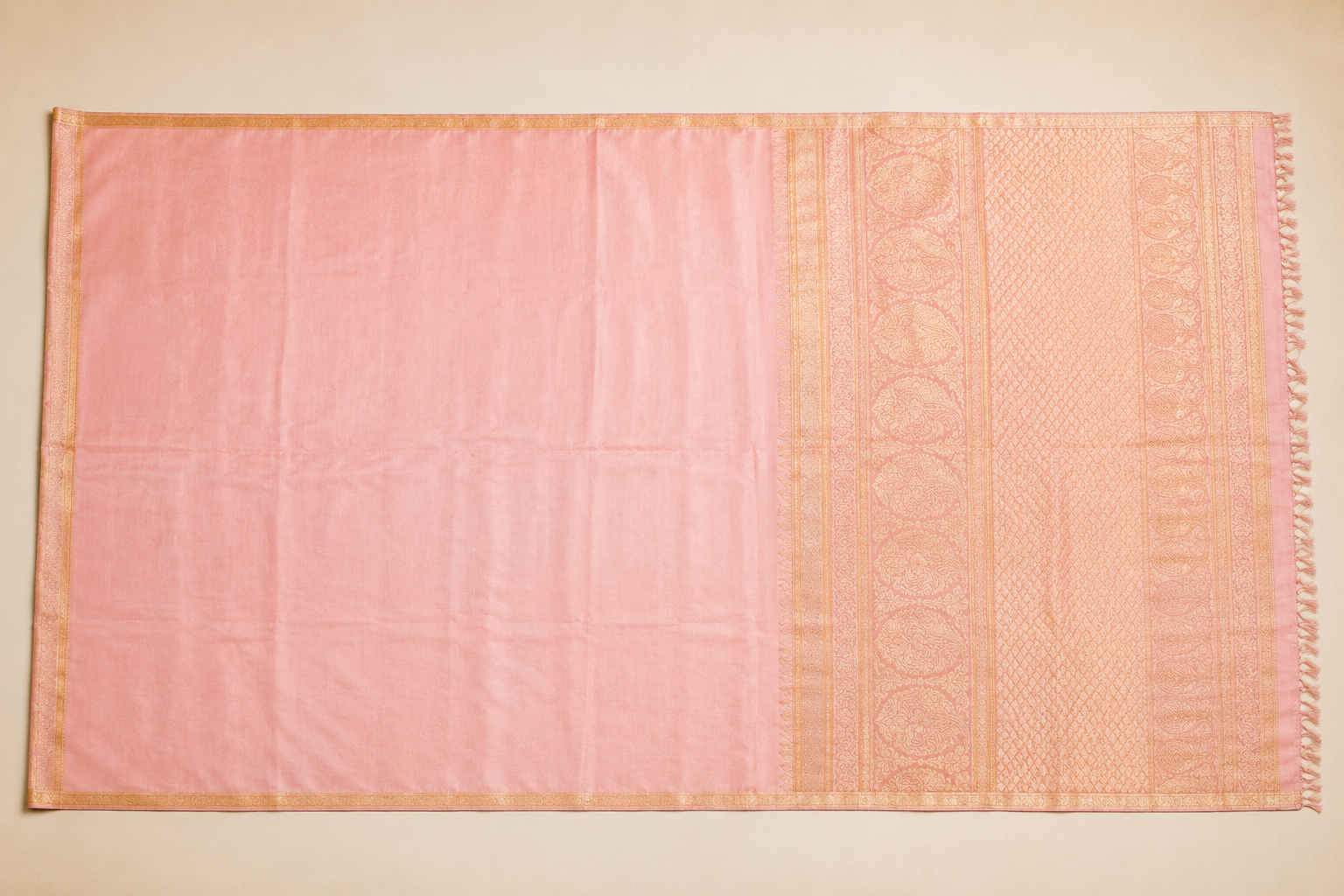 A pastel pink silk saree unfolded showing its full length and pallu