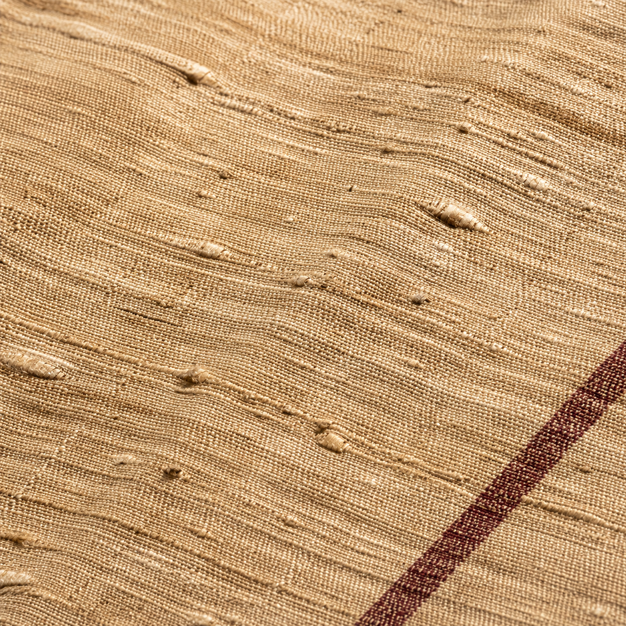 Macro detail of tussar silk fabric showing the distinctive slubby uneven texture of wild silk